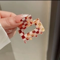 Close-up of a red and cream checkered acetate square hair claw clip held by fingers - Brown Checkerboard