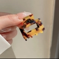 Detail of a mini leopard print acetate hair claw clip held in hand for scale and size - Dark Tortoiseshell