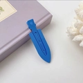 Blue matte finish hair clip with streamlined design on a decorative purple book - Sapphire Blue