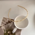 Detalle de una diadema ondulada en color beige sobre una taza de cerámica blanca - Blanco Crema