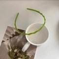 Detalle de diadema ondulada verde con dientes antideslizantes sobre una taza blanca - Verde Manzana