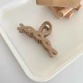 Matte beige crossover hair claw clip for thick hair displayed on a minimalist tray - Twisted Chain / Milk Coffee