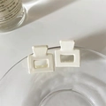 Close-up of two matte white rectangular claw clips on a glass rim in soft light - White