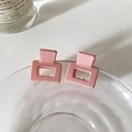 Close-up of two pink matte square hair claws clipped on a glass for hair styling - Pink