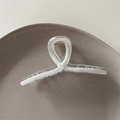 Detail shot of a minimalist acrylic hair claw clip with golden metal spring on a tray - Milky White