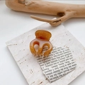 Macro shot of amber translucent small hair claw clip on white marble surface - Milk Brown Marble