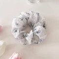 Gros plan d'un chouchou floral blanc et bleu avec texture à carreaux sur fond minimaliste - Bleu
