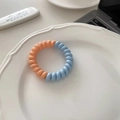 Vue détaillée de l'élastique à cheveux spirale bicolore en bleu pastel et orange doux - Orange Bleu