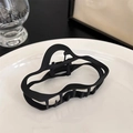 Détail d'une grande pince à cheveux noire mate avec des lignes ondulées sur un plat blanc - Noir