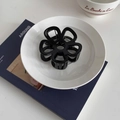 Pinza per capelli a fiore traforato nero lucido su piatto bianco in vista a 45 gradi - Nero