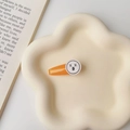 Close-up of bright orange duckbill hair clip with funny face design on a ceramic plate - Orange-XX Expression