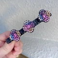 Dettaglio di un fermaglio per capelli nero con tre fiori scintillanti in strass multicolore - Colorato