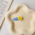 Blue hair clip with yellow smiley face on cream floral tray with book prop - Blue-Smiley Face