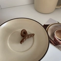 Close-up of a brown flocked hair claw clip on a ceramic tray in a warm lifestyle setting - Bobby Pin / Brown