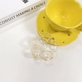 Dettaglio di un fermaglio per capelli a fiore traforato con molla dorata su base bianca - Bianco trasparente