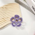 Detailed macro view of a purple hollow flower hair claw clip on a textured wood surface - Purple