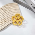 Close-up of yellow hollow flower hair claw clip with matte finish on wood background - Yellow