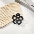 Close-up of black matte flower hair claw clip with metal spring on wooden surface - Black