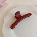 Detalle de una pinza para el pelo grande en color burdeos mate sobre un plato de cerámica blanco - Burdeos