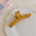 Vista de detalle de pinza para el cabello amarillo mate en bandeja de cerámica blanca - Amarillo jengibre