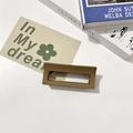 Dettaglio macro della molletta per capelli marrone opaca su scrivania minimalista - Marrone