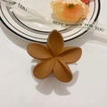 Detalle de pinza de pelo de flor mate en color caramelo sobre un plato decorativo blanco - Caramelo