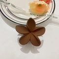Detalle de una pinza para el cabello de flor marrón mate en un plato de cerámica blanca - Café