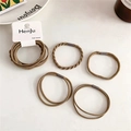 Detail of 5-piece earthy tone braided hair ties on a minimalist marble background - Coffee Colors
