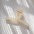 Macro detail of geometric textured cream hair claw with metallic gold spring and light shadows - Transparent Milky White