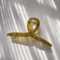 Detailed view of amber resin hair claw with geometric facets and golden metal spring - Transparent Tea