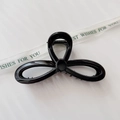 Close-up of a large black glossy hair claw clip with a sleek clover-shaped design on silk - Glossy Black