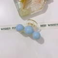 Dettaglio di un fermaglio per capelli in acrilico con perle blu e molla in metallo - Tre Perle Blu