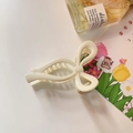 Detalle de una pinza para el cabello color crema con forma de lazo en un escritorio blanco - Blanco Lechoso