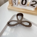 Dettaglio della grande pinza per capelli opaca marrone scuro su un vassoio bianco - Caffè Opaco