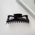 Macro shot of large glossy black claw clip showing multi-tooth grip and polished texture - Black