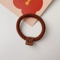 Detail of coffee brown braided hair tie featuring a square leather smiley face patch - Twisted Chain / Brown