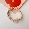 Close-up of a beige elastic braided hair tie featuring a cute smile face fabric label - Chain Style / Off White