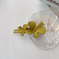 Détail d'une pince à cheveux papillon jaune moutarde mate sur un plateau décoratif - Jaune Papillon