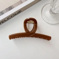 Dettaglio di un grande fermaglio per capelli in acrilico marrone scuro con molla dorata - Albicocca