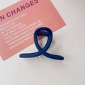 Close-up of a matte dark blue hair claw clip with a twisted cross design on a desk - Matte Blue