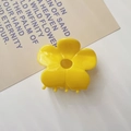Macro view of bright yellow acetate flower hair claw clip with glossy finish and teeth - Yellow