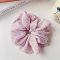 Primo piano dell'elastico in chiffon rosa con motivi floreali viola e consistenza increspata - Viola