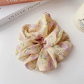 Texture dettagliata dello scrunchie in chiffon giallo chiaro con motivi floreali viola - Giallo