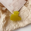 Detail view of a yellow acetate hair claw clip with geometric design on aesthetic paper - Milky Green