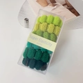 Close-up of seamless green hair ties in a clear box with macro texture detail - Green Series