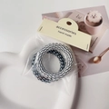 Detail of two black and white spiral telephone wire hair ties on a white heart tray - Black & White Stripes