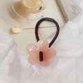 Detalle de una goma de pelo con flor de resina rosa sobre fondo de papel arrugado blanco - Rosa