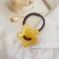 Detalle de una goma para el pelo con flor de resina amarilla sobre banda negra elástica - Amarillo