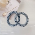Detailaufnahme der Spirale-Haargummis mit klassischem Schwarz-Weiß-Schachbrettmuster-Design - Schwarzes Schachbrett
