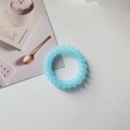 Detalle de la goma para el pelo en espiral azul claro sobre escritorio blanco liso - Azul Cielo